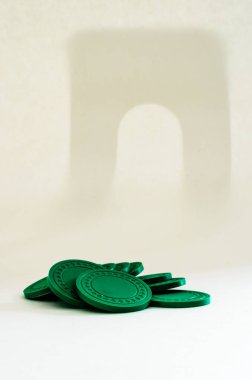 Beyaz arkaplanda arka planda gölgeli yeşil poker çiplerinin dikey görünümü.