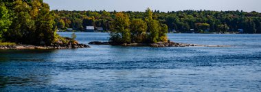 Bin Adalar arasında daha büyük bir tanesinin yanında yer alan küçük bir ağaç örtüsü etrafında St. Lawrence Nehri 'nin aktığını gösteriyor..