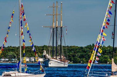 Yelkensiz uzun gemi yelkenli yelkenli yelkenli yelkenli bayrakları ile mavi gökyüzünde dalgalanıyor.