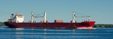 St. Lawrence Seaway 'de berrak gökyüzü olan yalnız ve paslı bir geminin panoraması..