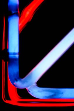 Siyah zemin üzerinde açılı tüpler bulunan kırmızı ve mavi neon ışık desenlerinin dikey çerçevesi