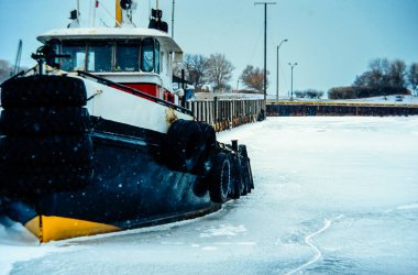 Limandaki donmuş suda römorkör Mavi, berrak bir gökyüzünün altında iskelenin yanında..