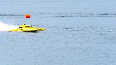 Sarı bir deniz uçağı spreyi fırlatıyor. Mavi su üzerinde ilerlerken bir yaz günü turuncu bir topun yanından geçiyor.