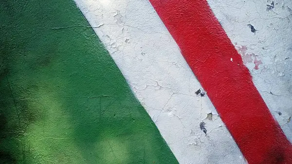 Beyaz çizgili yeşil ve kırmızı çizgili bir duvar. Duvar grafiti ile kaplanmış.