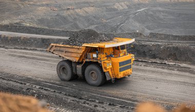 Large quarry dump truck. Big yellow mining truck at work site. Loading coal into body truck. Production useful minerals. Mining truck mining machinery to transport coal from open-pit production. clipart