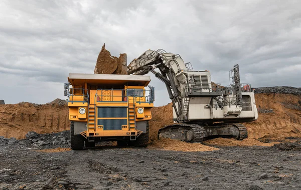 大採石場のダンプトラックと掘削機 大きな鉱山トラックは石炭鉱床を働かせます 石炭をトラックに積み込む 有用な鉱物を生産する 露天掘り生産から石炭を輸送する鉱山機械 — ストック写真