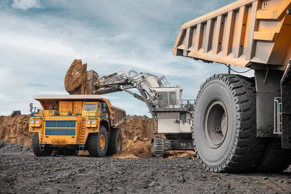 Large quarry dump truck and excavator. Big mining truck work coal deposit. Loading coal into body truck. Production useful minerals. Mining mining machinery to transport coal from open-pit production.