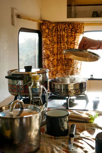 Adamın biri gün batımında bir karavanda yemek pişiriyor. Gün batımında bir karavanda romantik bir akşam yemeği. Yapıştır.