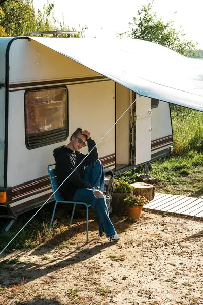 Bir kız gün batımında kafasında çay şapkası olan bir karavanın yanında oturur. Kız kahve içiyor. Gezgin.