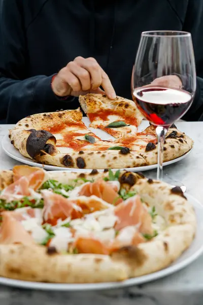 Genç moda eğlence adamı bir bardak şarapla pizza yiyor. Güneş gözlüğü, harika tasasız bir gün, şehir tarzı.