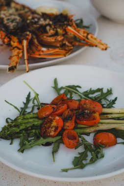 Gourmet seafood dinner with grilled lobster, roasted vegetables, and white wine on a fancy stylish table setting clipart