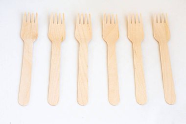 Tek kullanımlık çevre dostu tahta çatallar beyaz arka planda. Beyaz arka planda çevre dostu tek kullanımlık ahşap çatal bıçak takımı.