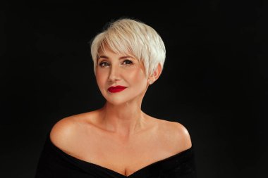 Kısa sarı saç stili ve göz kamaştırıcı makyajlı, siyah stüdyo arka planında kırmızı dudaklı zarif bir kadının güzel portresi..