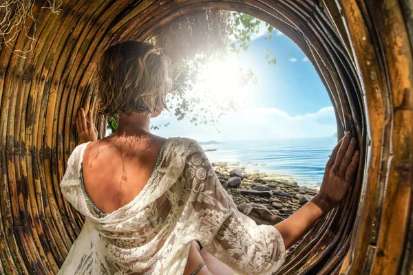美しい 日当たりの良いビーチでリラックスした女性のバックビューでは 海と青い空を見て 竹のBohoスイングに座っている — ストック写真