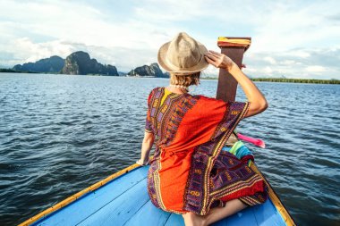 Tayland 'daki tropikal adalarda geleneksel uzun kuyruk teknesiyle seyahat turu. Kadın oturuyor ve rahatlıyor, manzaraya bakıyor. Asya 'da yaz tatilleri