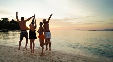 Group of friends having fun on the beach during sunset, having fun and jumping. Young people enjoying summer vacation. Travelers. Tourism