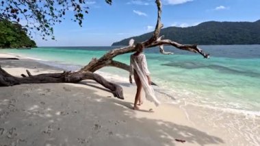 Calm, happy woman in black bikini and sunglasses relaxing on the tropical beach. Fit tanned body. Paradise island in Thailand, Asia. Travel. Tourism.
