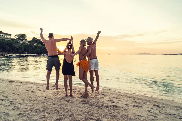 Glada Vänner Som Njuter Vacker Solnedgång Den Tropiska Stranden Hoppar — Stockfoto