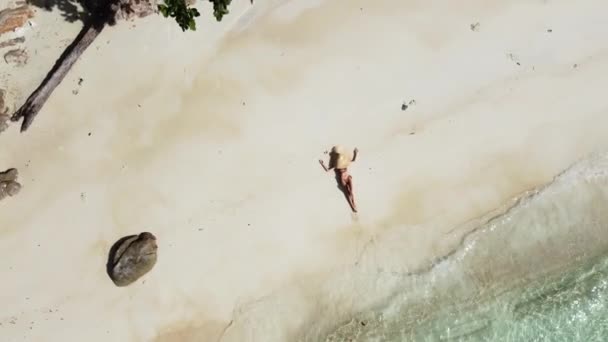 热带海滩上悠闲女子的空中照片 女孩头戴大帽子躺在白沙滩上 旅行人员 — 图库视频影像
