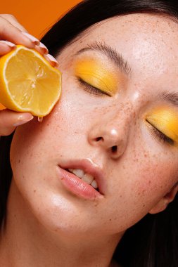 Güzel kadın sağlıklı cildine doğal çillerle sulu limon meyvesi sıkıyor. Temiz cilt bakımı kavramı, kozmetoloji