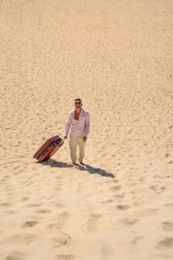 Bavullu bir adam çölde yürüyor. Bir sürü kopya alanı var. Kavramsal fotoğraf. Turizm. Gezgin
