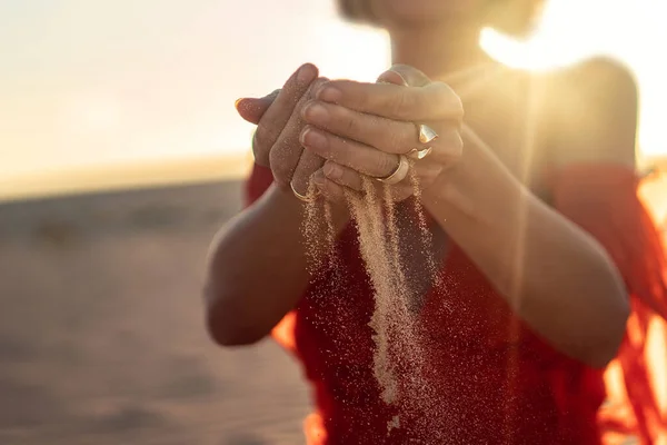 日落时分 一个优雅的女人 手中的沙子落在海滩上 金色的光概念性照片 — 图库照片