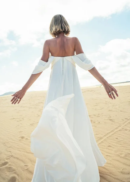 照片上的一个女人穿着漂亮的白色婚纱在沙漠中摆姿势 — 图库照片