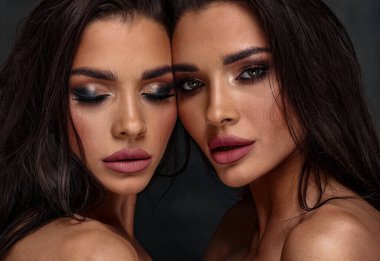 Çekici makyajlı iki seksi kadının güzel fotoğrafı. Bir kız kameraya bakıyor, ikincisinin gözleri kapalı. Yakın plan portre.