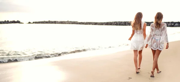 砂のビーチで一緒に歩いて2人のブロンドの女性のバックビューでは 手を握って 友情の概念 全長写真 — ストック写真
