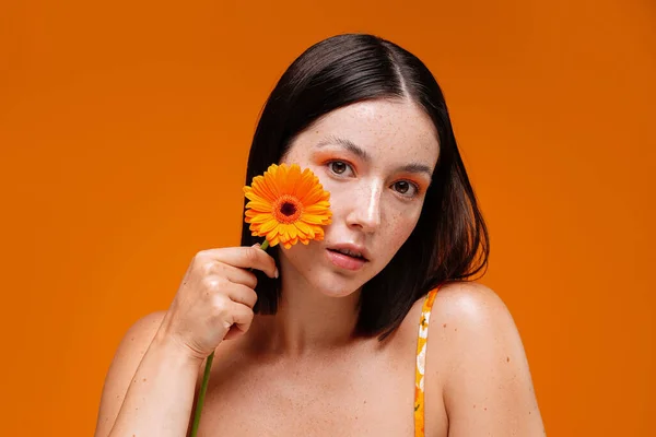 Portret Młodej Naturalnej Piegowatej Kobiety Kwiatem Twarzy Odizolowanej Pomarańczowym Tle — Zdjęcie stockowe