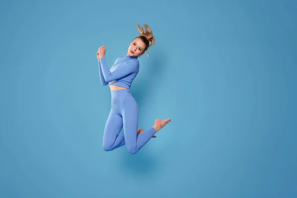 Vrolijke Sportieve Vrouw Modieuze Sportkleding Springt Een Blauwe Studioachtergrond Sport — Stockfoto