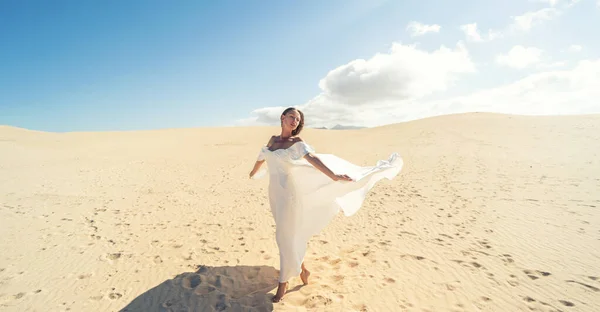 ファッショナブルな マキシ社の白いウェディングドレスは 砂漠の上にポーズで穏やかな女性は 日当たりの良い光の中で踊り コピースペースの多く 花嫁になる — ストック写真