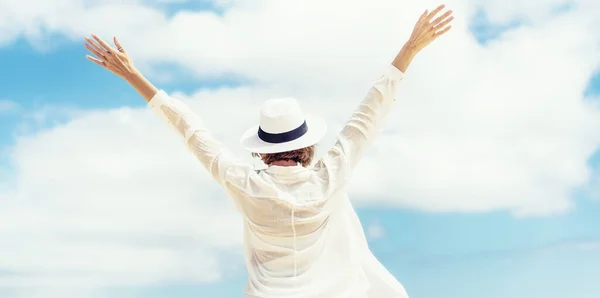 手を上げて幸せな女性のバックビューの写真 白いシャツと夏の帽子を身に着けている女の子白い雲と空を見て — ストック写真
