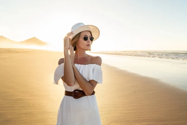 Modna Kobieta Białej Sukience Letnim Kapeluszu Pozująca Piaszczystej Pięknej Plaży — Zdjęcie stockowe
