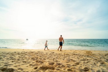 Baba ve oğul yaz plajında yürüyor. Baba ve çocuk dışarıda eğleniyor. Aile seyahati, tatil, babalar günü konsepti.