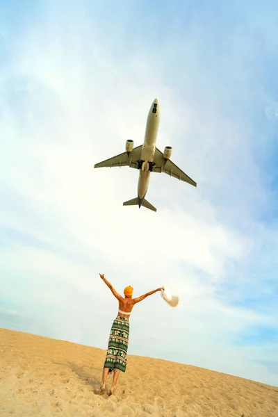 stock image Photo of airplane flies extremely low over the sandy beach and one tourist woman. Travel and tourism concept. Thailand. 