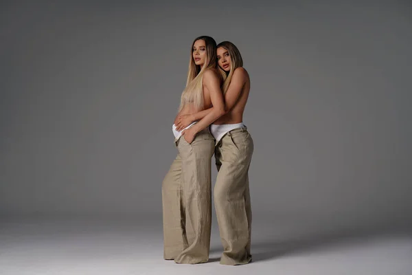 Dos Mujeres Embarazadas Moda Posando Juntas Estudio Pie Abrazando Mirando —  Fotos de Stock