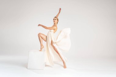 Gri ışıklı stüdyo arka planında dans eden zarif elbiseler giyen genç sarışın dansçı. Uzayı kopyala Balerin. Hobi.