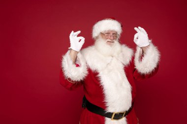 Mutlu gerçek Noel Baba gülümsüyor, kırmızı stüdyoda poz veriyor..