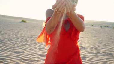 İçinden kum akan bir kadının elleri. Arka planda kum tepecikleri. Gün batımı sıcak gün ışığı. Yaz titreşimleri. Özgürlük için. Doğa. 