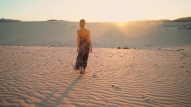 Gün batımında çölde yürüyen bir kadın, dinleniyor. Sakin ol kızım. Ilık doğal ışık. Özgürlük için. Turist. 