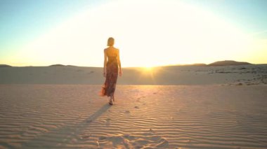 Gün batımında çölde yürüyen bir kadın, dinleniyor. Sakin ol kızım. Ilık doğal ışık. Özgürlük için. Turist. 