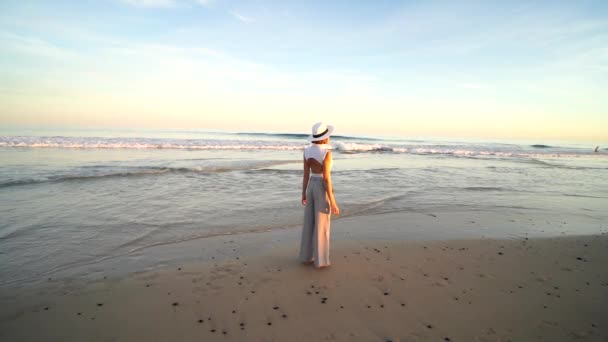 Μοντέρνα Γυναίκα Στέκεται Στην Αμμώδη Παραλία Κατά Διάρκεια Του Ηλιοβασιλέματος — Αρχείο Βίντεο