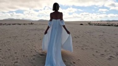 Fuerteventura Adası, kumullarda poz veren güzel beyaz gelinlikli kadın.