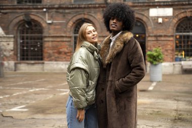 Modaya uygun, çok ırklı bir çift dışarıda poz veriyor. Sonbahar tarzı. Kafkasyalı sarışın kadınla Afro adam.