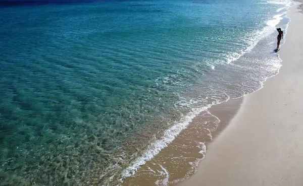 海岸に浮かぶ海の波で砂浜を歩く女性の空中視界 夏のバイブ サルデーニャ トラベルコンセプト ストックフォト