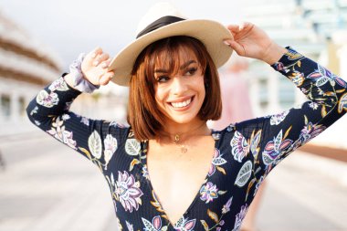 Sağlıklı beyaz dişleriyle gülümseyen, yaz şapkası takan muhteşem bir genç kadın. Mutlu bir kadın. Güneşli bir gün. 