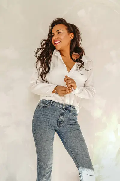 漂亮的女人穿着牛仔裤和白衬衫 面带微笑 随意的日常风格 时髦的女士 图库照片
