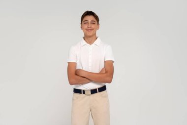 Beyaz gömlekli, şık giyinen, stüdyoda poz veren genç bir çocuk. Beyaz arka planda gülümseyen ve kameraya bakan yakışıklı bir gencin portresi.