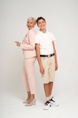 Mutlu genç çocuk açık gri stüdyo arka planında zarif annesiyle poz veriyor ve bir sürü fotokopi alanı var. Kadın oğluyla eğleniyor. Anneler Günü konsepti